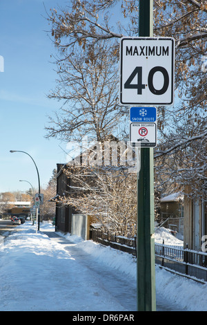 Street signs with speed limit of 40 km per hour and no-parking tow-away zone when the street is designated as a snow route. Stock Photo