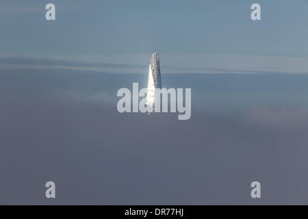 London, UK, 21st Jan 2014. The top of The Shard, just visible above the low fog that swathes the capital, catches the early morning sunlight. Viewed from Canary Wharf. At 306m, The Shard is currently the tallest building in the EU Credit:  Steve Bright/Alamy Live News Stock Photo