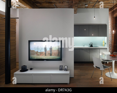 Television on wall with kitchen area behind, Albert Mill, Manchester, Greater Manchester. Stock Photo