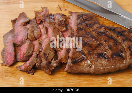 Marinaded flank steak, or London broil, sliced thinly against the grain on a wooden chopping board. Stock Photo