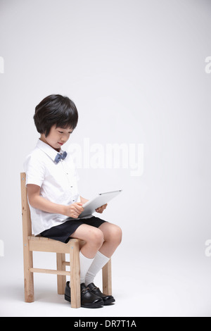 a boy using tablet PC on a chair Stock Photo