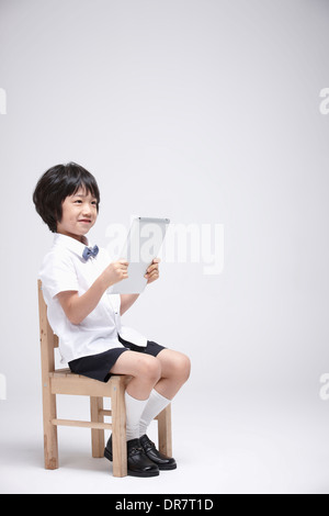 a boy using tablet PC on a chair Stock Photo