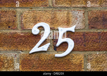 The number 25 attached to a brick wall. Stock Photo