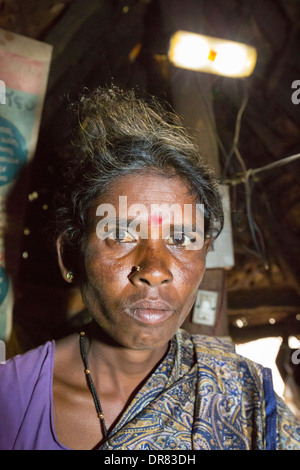 An untouchable woman in her hut, illuminated by an electric light, powered by an A4 sized solar panel, that charges a battery, and enables her to have light. The prrject was sponsored by the Rotary club. Before the installation of the solar panels, the houses would be lit by kerosene lamps. Over 1 million women and children die every year in india from inhaling kerosene fumes. Stock Photo