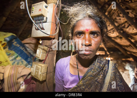 An untouchable woman in her hut, illuminated by an electric light, powered by an A4 sized solar panel, that charges a battery, and enables her to have light. The prrject was sponsored by the Rotary club. Before the installation of the solar panels, the houses would be lit by kerosene lamps. Over 1 million women and children die every year in india from inhaling kerosene fumes. Stock Photo