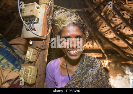 An untouchable woman in her hut, illuminated by an electric light, powered by an A4 sized solar panel, that charges a battery, and enables her to have light. The prrject was sponsored by the Rotary club. Before the installation of the solar panels, the houses would be lit by kerosene lamps. Over 1 million women and children die every year in india from inhaling kerosene fumes. Stock Photo