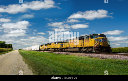 Lincoln Highway gravel road alongside the railroad tracks where the Union Pacific train is running near to Ashton, Illinois Stock Photo