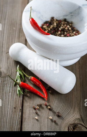 Mortar with different kinds of pepper and rosemary sprigs Stock Photo