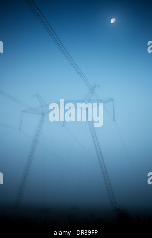 Power lines and pylons in fog in the early morning Stock Photo