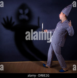 frightened man with candle in pajamas Stock Photo