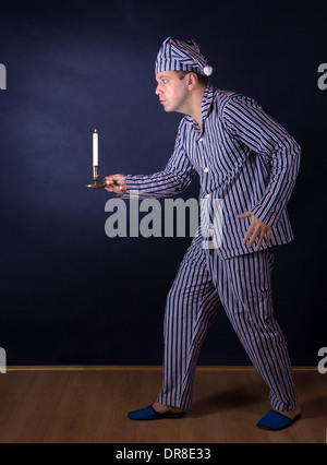 frightened man with candle in pajamas Stock Photo