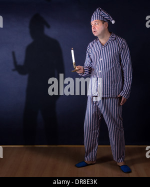 frightened man with candle in pajamas Stock Photo