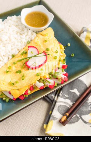 Omelet stuffed with strips of kamaboko, a japanese white fish cake, green onions and American cheese, with rice and shoyu butter Stock Photo