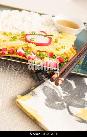 Omelet stuffed with strips of kamaboko, a japanese white fish cake, green onions and American cheese, with rice and shoyu butter Stock Photo