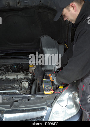 Auto mechanic measuring car battery voltage using multimeter Stock Photo