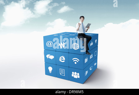 a business man sitting on a cube with icons Stock Photo