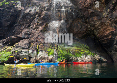 Sea kayaking beneath a waterfall along the Slieve League cliffs, County Donegal, Ireland. Stock Photo