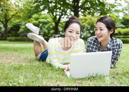 university students lying on grass working with a laptop Stock Photo