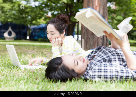 university students lying on grass working Stock Photo