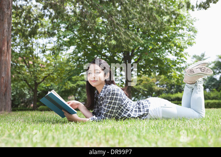 a university student lying on grass reading a book Stock Photo