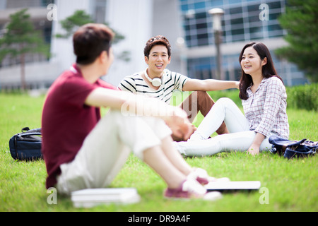 students sitting on grass having a conversation Stock Photo