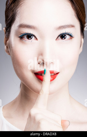 close up shot of a woman with a finger in her red lips Stock Photo