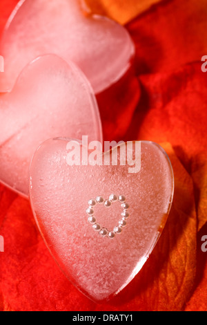 Heart shape embedded in an ice heart on artificial rose petals Stock Photo