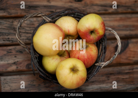 A bushel of red apples in a rustic wooden basket Stock Photo