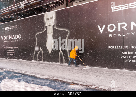 A worker shovels the sidewalk during a snow storm in Times Square Stock Photo