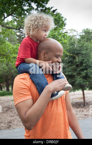 Happy father carrying son on shoulders Stock Photo