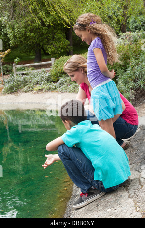 Curious mother with children at riverbank Stock Photo