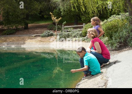 Curious mother with children at riverbank Stock Photo