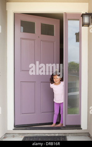 Little girl with open door at the entrance of house