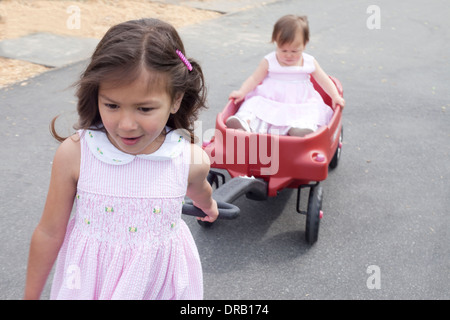 Girl pulling her younger sister in a red wagon Stock Photo - Alamy