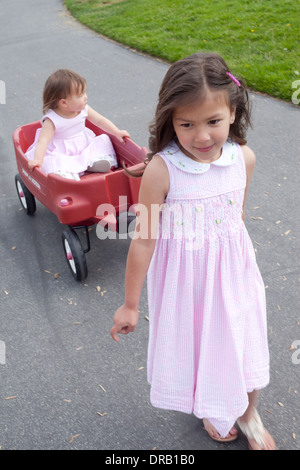 Girl pulling her younger sister in a red wagon Stock Photo - Alamy