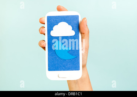 Conceptual phone showing a cloud and bird on blue background Stock Photo