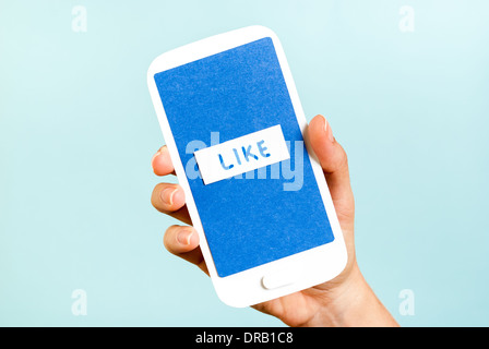 Conceptual smartphone showing like button on blue background Stock Photo