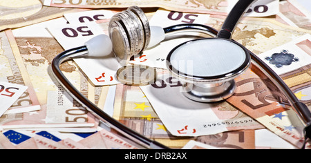 stethoscope surrounded by banknotes and coins suggesting the cost of medical investigation Stock Photo