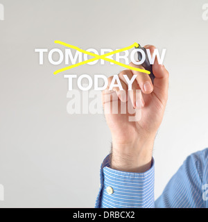 Businessman crosses off tomorrow for TODAY with yellow marker pen on the screen Stock Photo