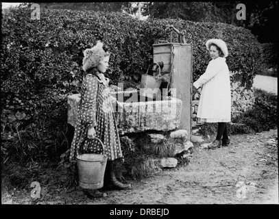 Portrait of two girls at the village water pump. Glass lantern slide of a photograph taken in 1905. Labelled 'Family Thompson at pump'. Beetham, Cumbria (then Westmorland), Lake District, England. Stock Photo