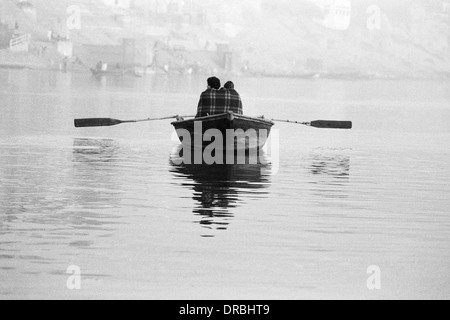 Couple wrapped in blanket boating on river Ganges, Varanasi, Uttar Pradesh, India, 1982 Stock Photo