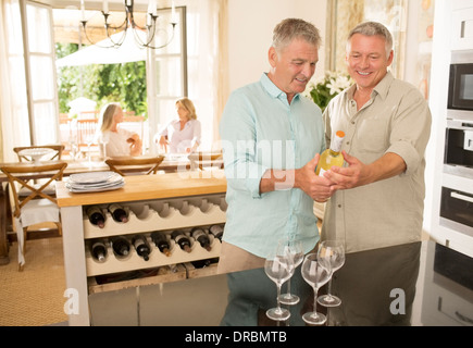 Senior me looking at wine bottle in kitchen Stock Photo