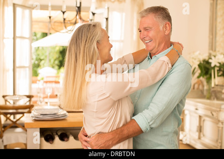 Senior couple hugging in kitchen Stock Photo