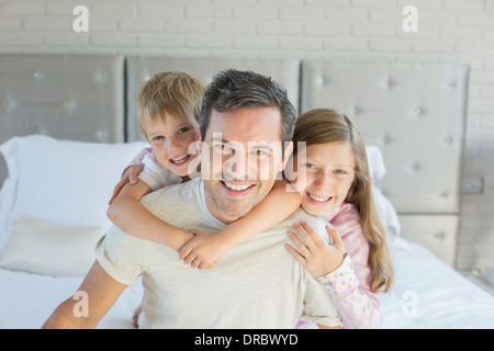 Father and children hugging in bedroom Stock Photo