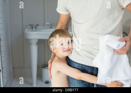 Boy hugging father in bathroom Stock Photo