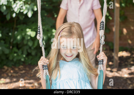 Father pushing daughter on swing Stock Photo