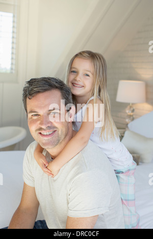 father with daughter embracing and looking at camera while mother with