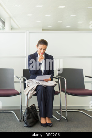 Businesswoman reading in waiting area Stock Photo
