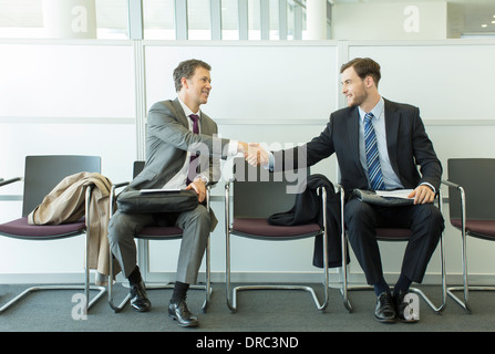 Businessmen shaking hands in waiting area Stock Photo