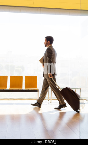 Businessman pulling suitcase in office Stock Photo